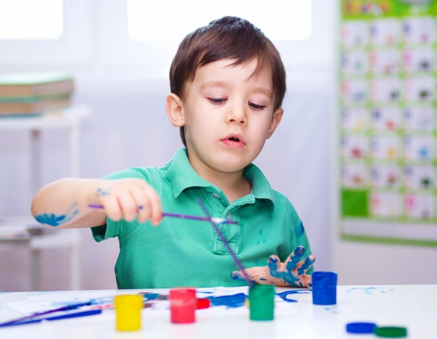 A young boy is playing with paint and scissors.