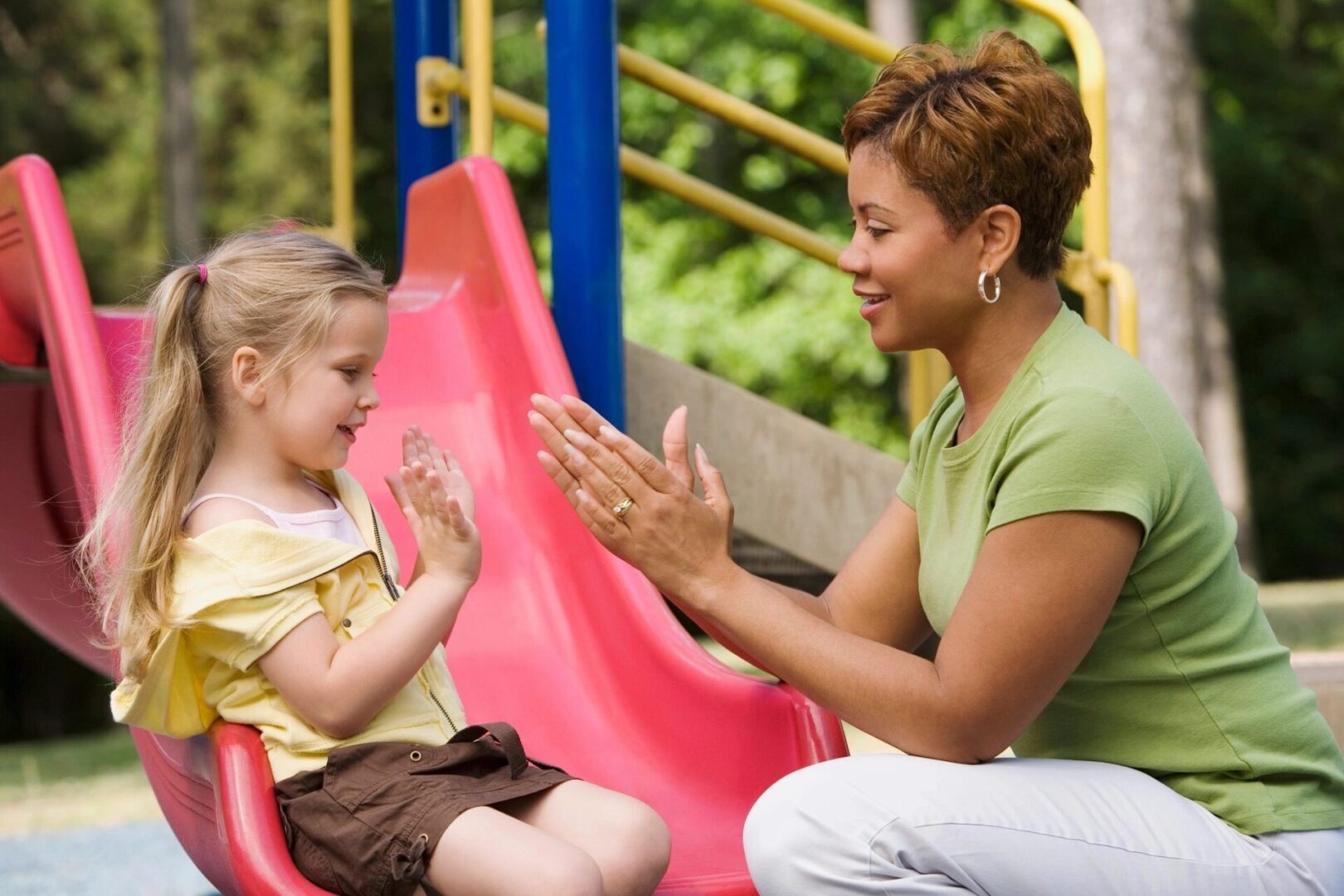 A woman and child sitting on slide talking.