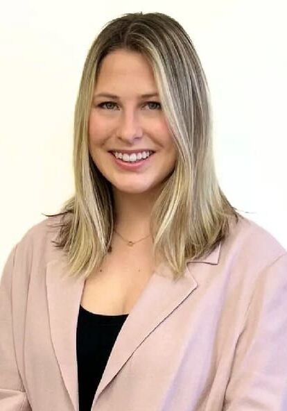 A woman in a pink jacket smiling for the camera.