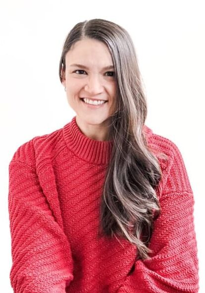 A woman in red sweater smiling for the camera.